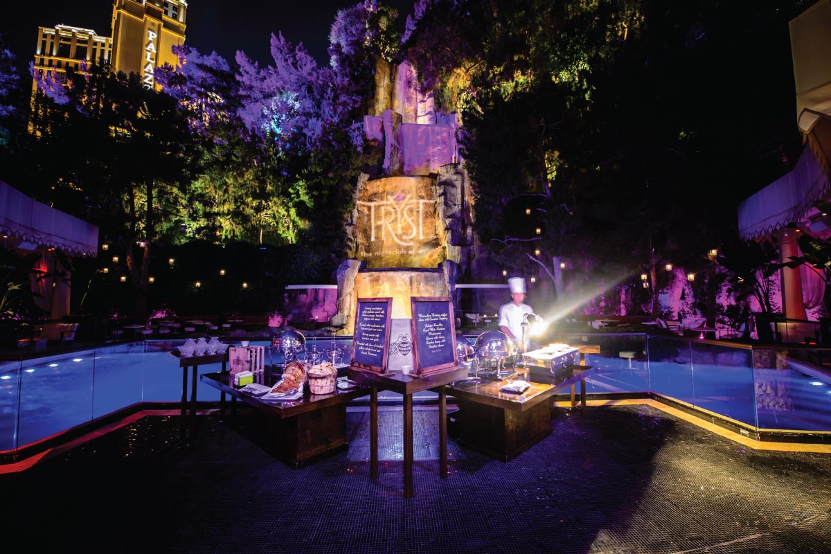 Tryst Nightclub event dinner food set up with chef outside at night with lit pool and greenery in the background